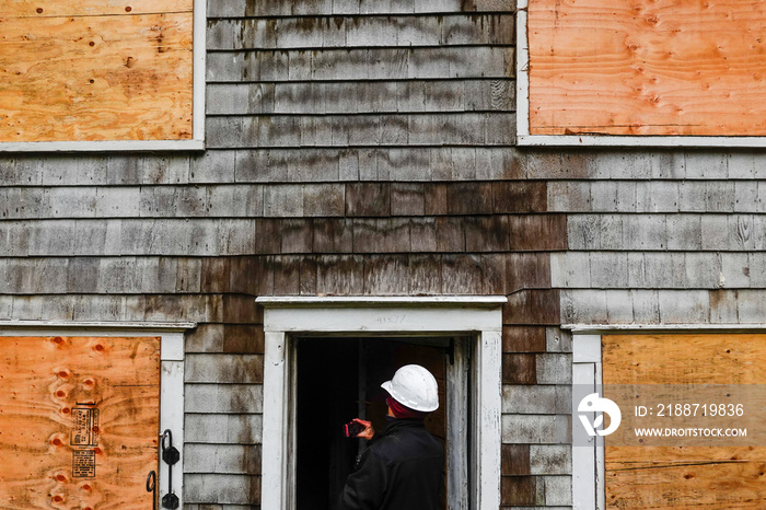 Cornwall, Ct, USA  An insurance fire inspector inspects the exterior  of a wooden house damaged by fire.