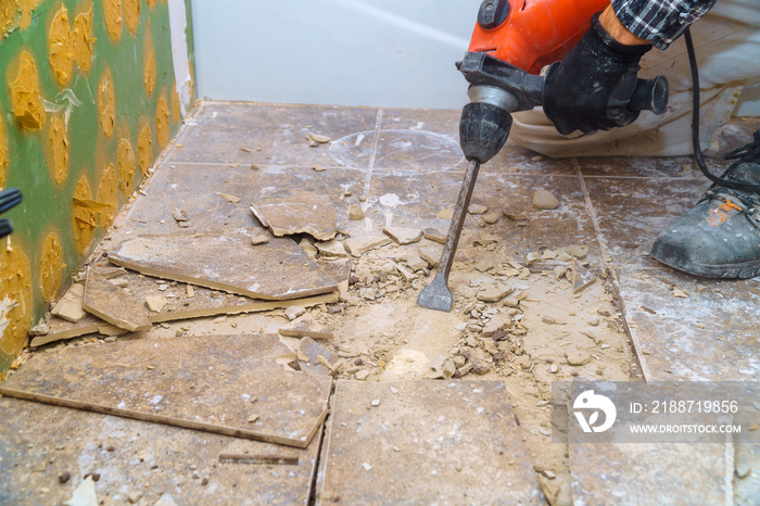 Worker remove, demolish old tiles a bathroom with jackhammer