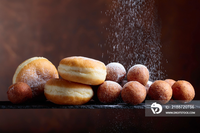 Sweet donuts powdered with sugar on a brown background.