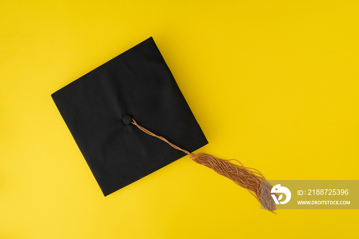 Graduation hat on yellow background. Student hat. Top view.