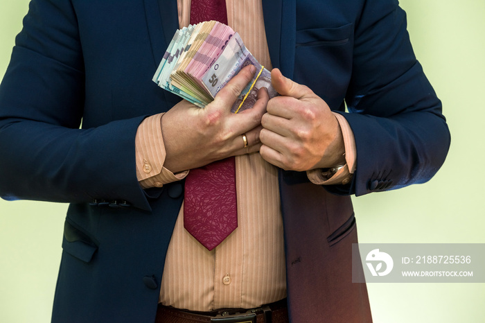 Business man hiding pack of Ukraine in suit pocket. The concept of corruption and fraud. UAH. 1000 new hryvnia banknotes