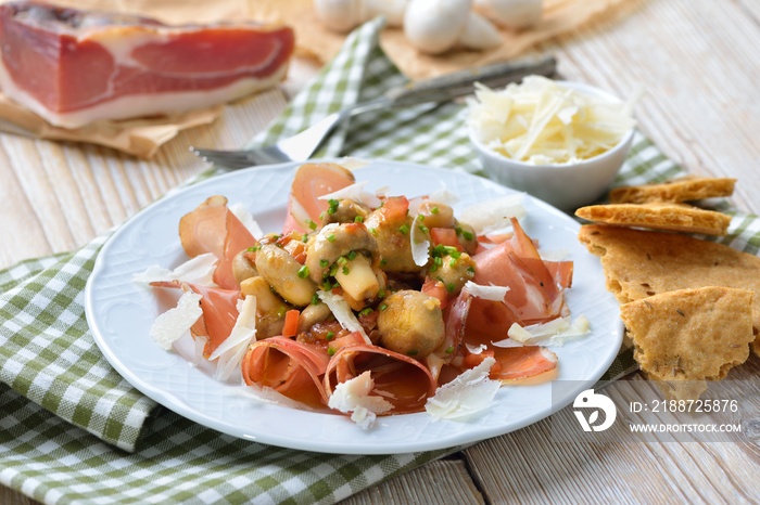 Lauwarmer Pilzsalat auf Südtiroler Speck mit Parmesan und Schüttelbrot serviert – Lukewarm mushroom salad on original South Tyrolean bacon, served with parmesan cheese and local rye flat bread