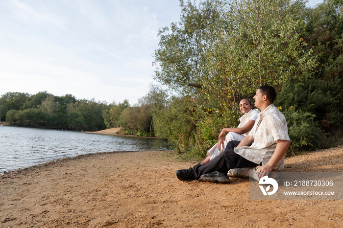 Smiling couple sitting on lakeshore