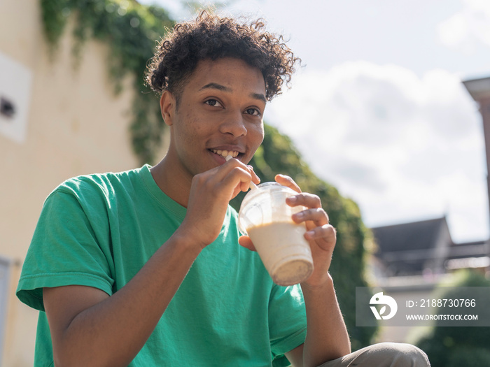 Portrait of young man drinking smoothie on sunny day