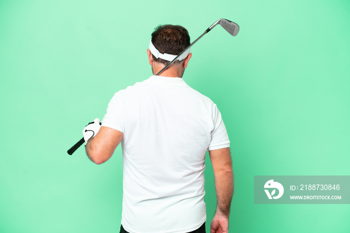 Middle age caucasian man isolated on green background playing golf and in back position