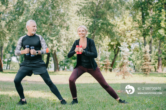 mature sportsman and sportswoman exercising with dumbbells in park