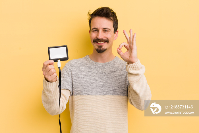 young handsome man feeling happy, showing approval with okay gesture. vip pass id