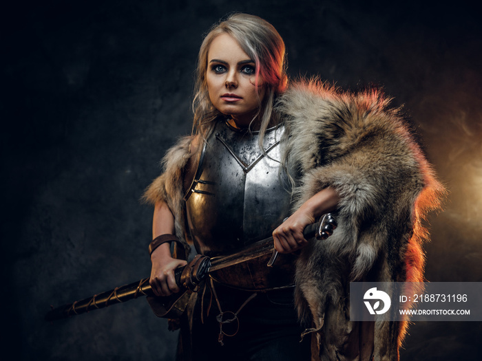 Fantasy woman knight wearing cuirass and fur, holding a sword scabbard ready for a battle. Fantasy fashion. Cosplayer as Ciri from The Witcher.