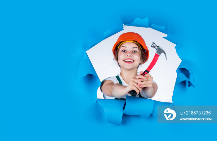 happy kid in helmet hold hammer. carpentry and woodworking concept. teen child using hammer tool. building and repair tools. repairman. small girl repairing in workshop. copy space