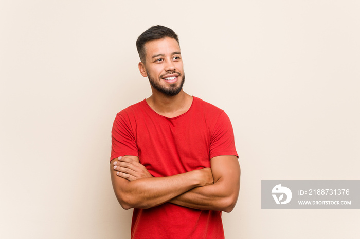 Young south-asian man smiling confident with crossed arms.