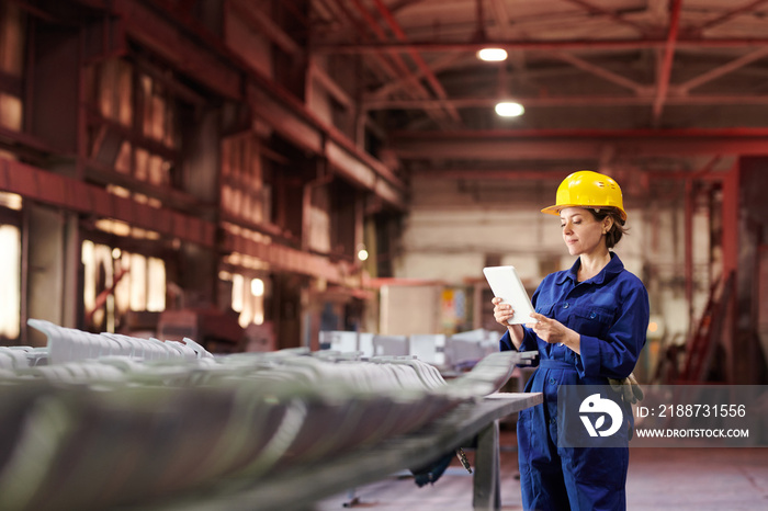 Side view portrait of female worker holding digital tablet while supervising production at factory, copy space