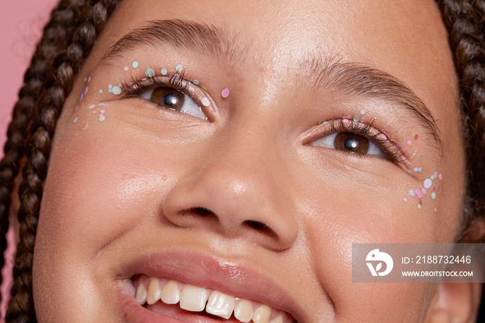 Close-up of smiling girl with decorative stickers on face