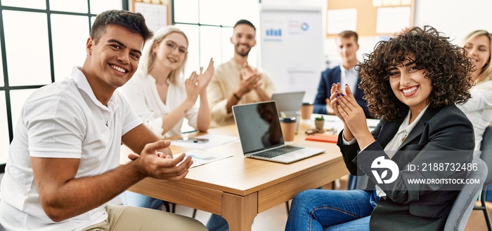 Group of young business workers clapping and looking to the camera at the office.