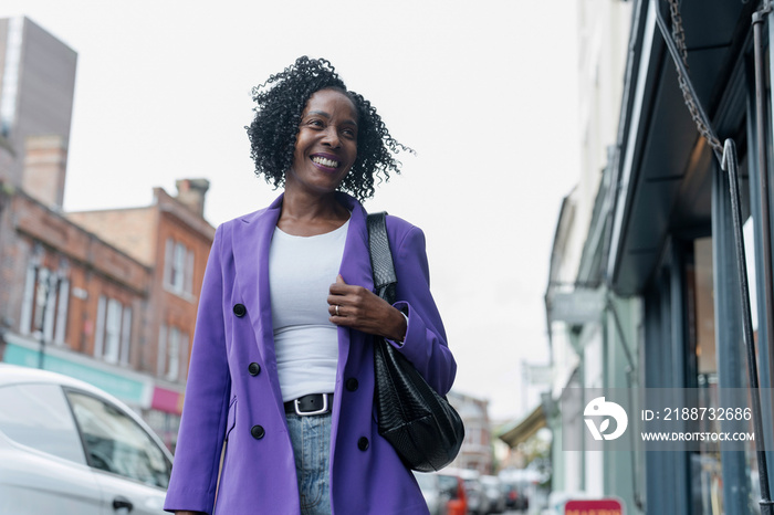 Smiling woman in purple jacket walking in city