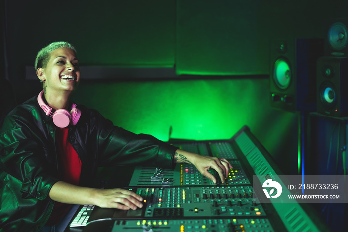 Young woman working in music recording studio - Female audio engineer mixing a sound in production house