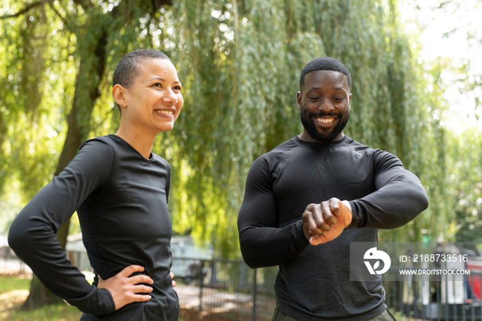 Smiling athletic man and woman standing in park