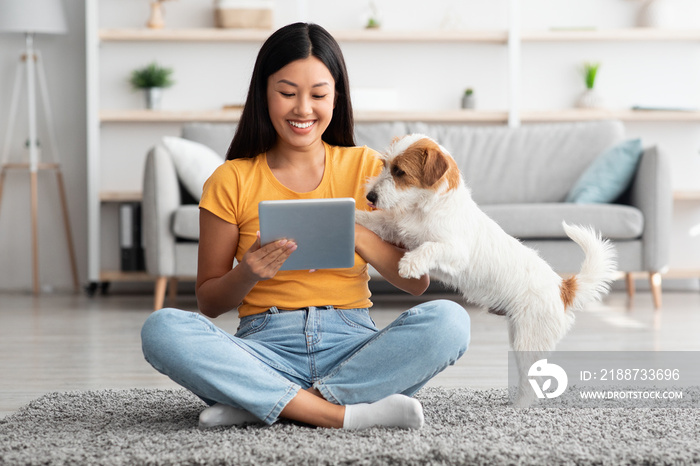 Asian woman and cute dog having fun together at home