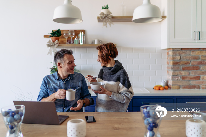 Men using laptop and driking coffee at home and talking with his wife