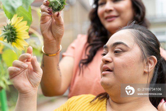 Mother with down syndrome daughter looking at flowers in garden