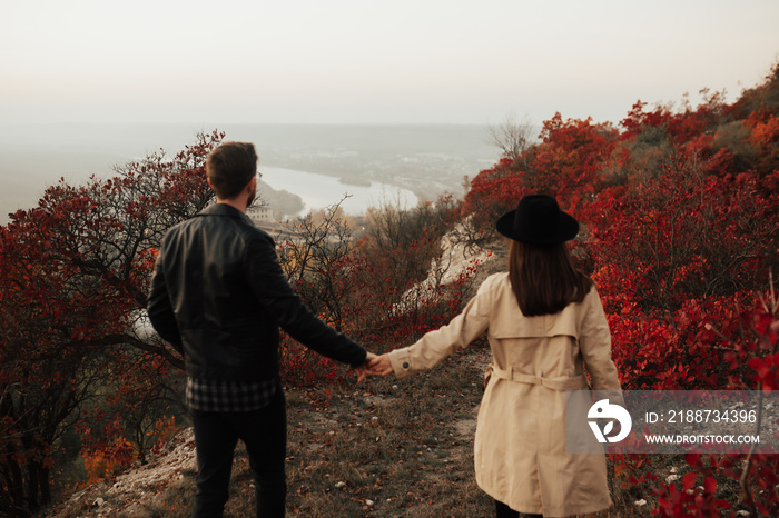 Stylish couple looking at beautiful autumn landscape, on hiking trip. COUPLE NO FOCUS, selective soft focus.