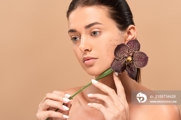 naked woman with problem skin holding orchid near face isolated on beige