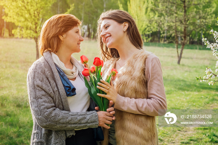 Daughter gives her senior mother tulips. Mother’s day present. Family values