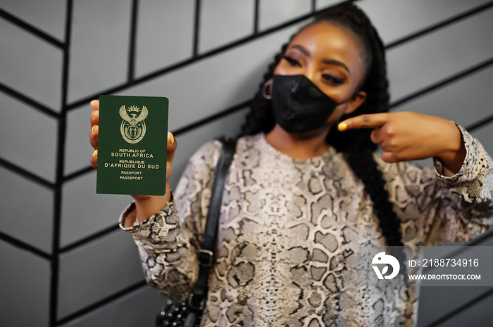 African woman wearing black face mask show South Africa passport in hand. Coronavirus in Africa country, border closure and quarantine, virus outbreak concept.