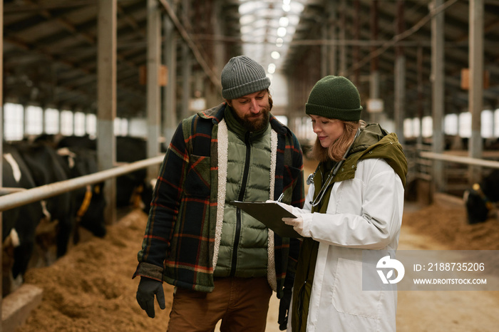 Veterinarian writing prescription after medical exam on farm and giving recommendations to farmer