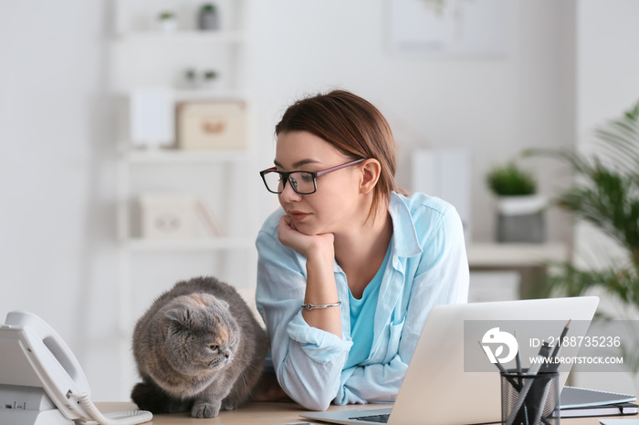 Young woman working with her cute cat in office