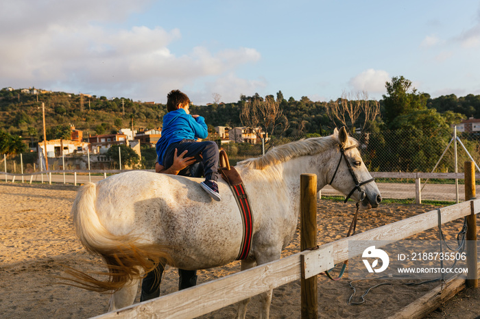 Child with a disability riding a horse in an equestrian center.