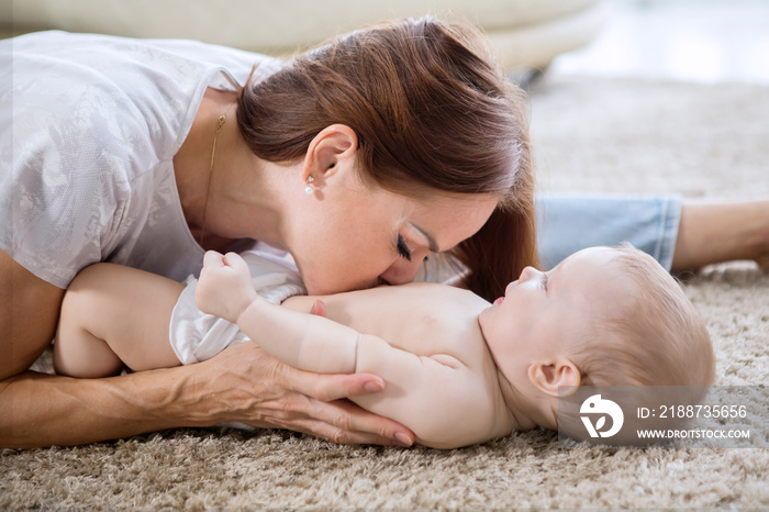 Mother kissing belly of her baby girl at home