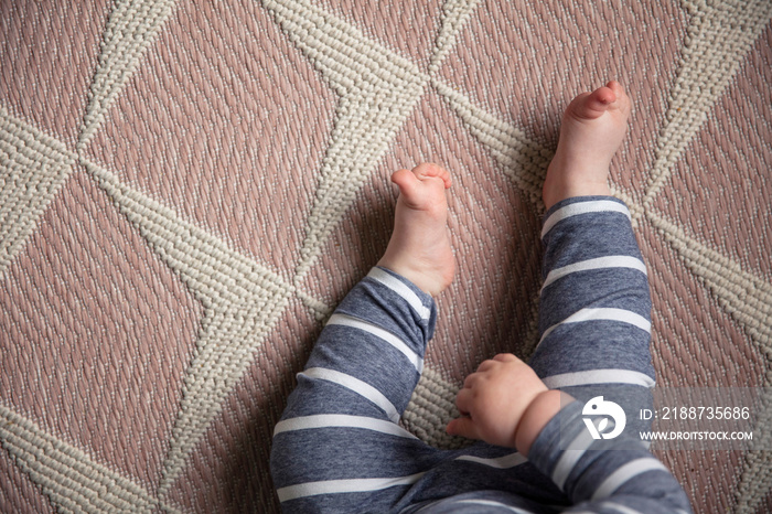 cute babies legs and toes sat on a pink nursery rug