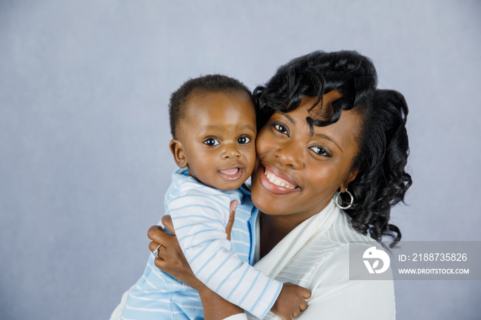 Beautiful African Amercian Woman wHolding Her Baby boy on a Gray Background