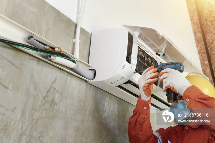 A young Asian air conditioner technician or air-conditioning installation technician is about to repair air conditioning in homes and buildings