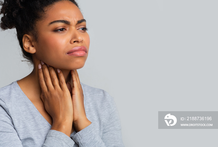 Afro woman suffering from sore throat, touching her neck