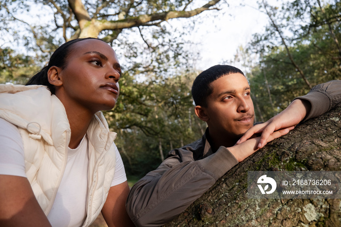 Portrait of couple leaning on tree branch