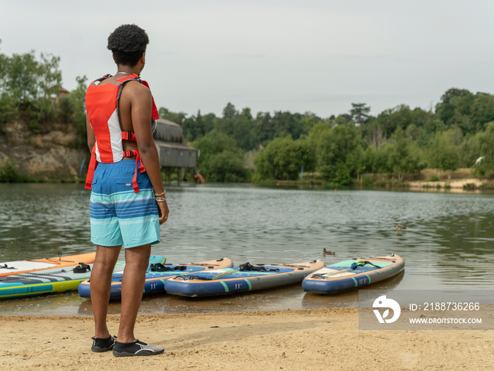 Young man looking at lake before paddleboarding