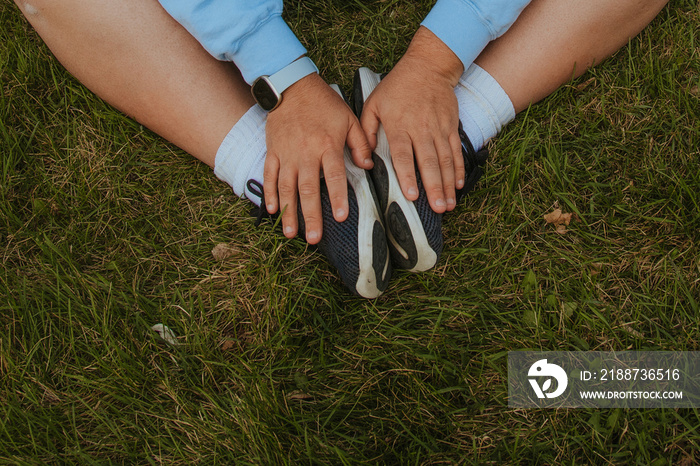 closeup of plus size hands on shoes against grass