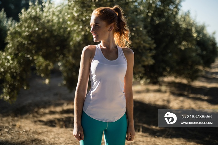 Smiling young woman looking away while standing on field