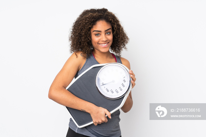 Young African American woman isolated on white background with weighing machine