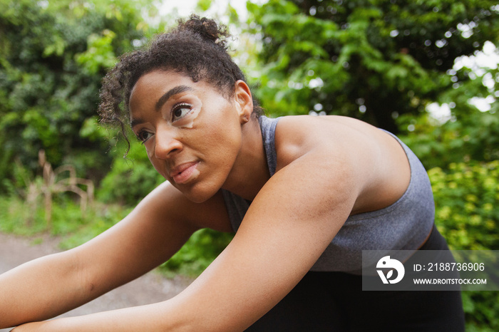 Young curvy woman with vitiligo stretching after workout in the park