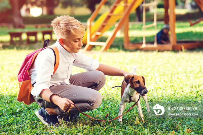 Schoolboy and his dog walking in the park.