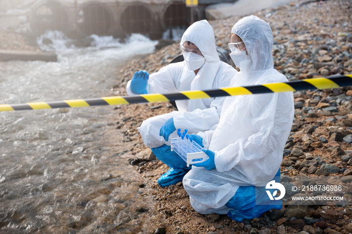 Scientist or Biologist in a protective suit and protect mask collects sample of waste water from industrial for analyze, problem environment, Ecologist sampling water from the river with test tube