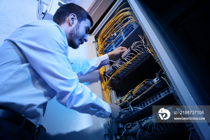 Handsome young engineer working in server room