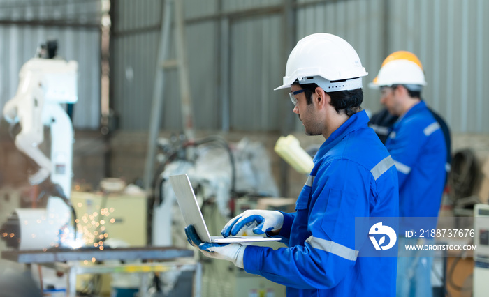 Group of engineers are manipulating a welding robot hand. By combining welding manipulation with a control panel