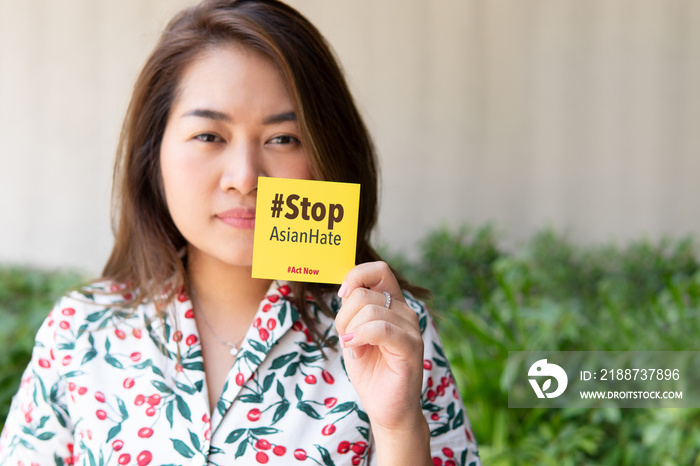 Stop asian hate hashtag, support Asian americans communities and Pacific Islanders campaign. A young beautiful asian woman hold a note  Stop asian hate  Against racism concept, Stop hate crimes, AAPI.