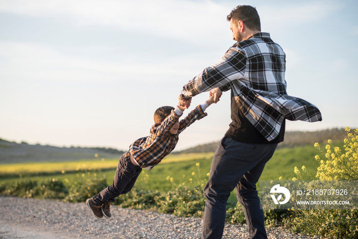 Spinning father grabbing his son with his arms