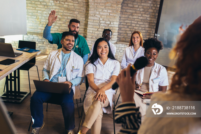 Doctor attending a seminar and raising his hand to ask a question