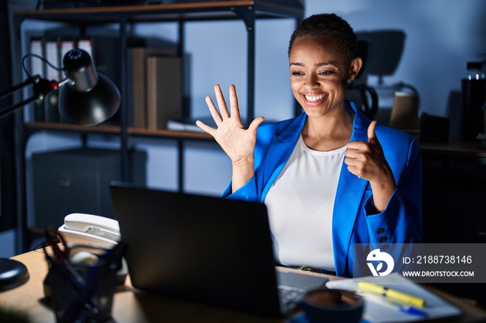 Beautiful african american woman working at the office at night showing and pointing up with fingers number six while smiling confident and happy.