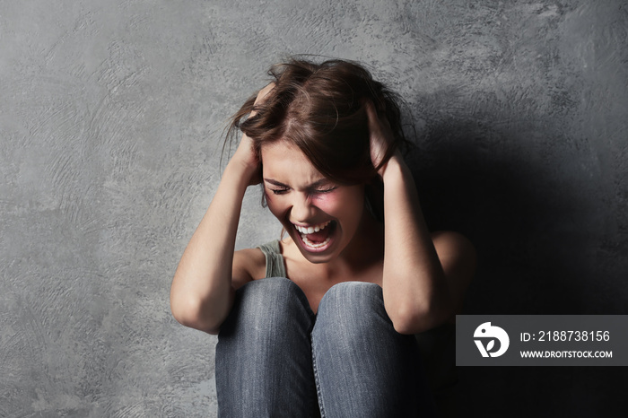 Battered young woman sitting near concrete wall